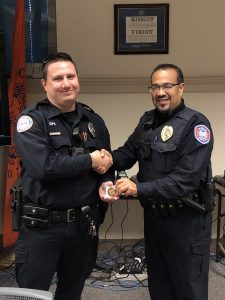 Officer Lebron presenting Officer Pearson with challenge coin while shaking hands.