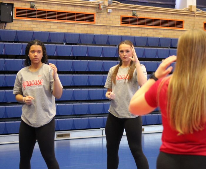 Officer Jewell teaches two members of the women's volleyball team self defense skills